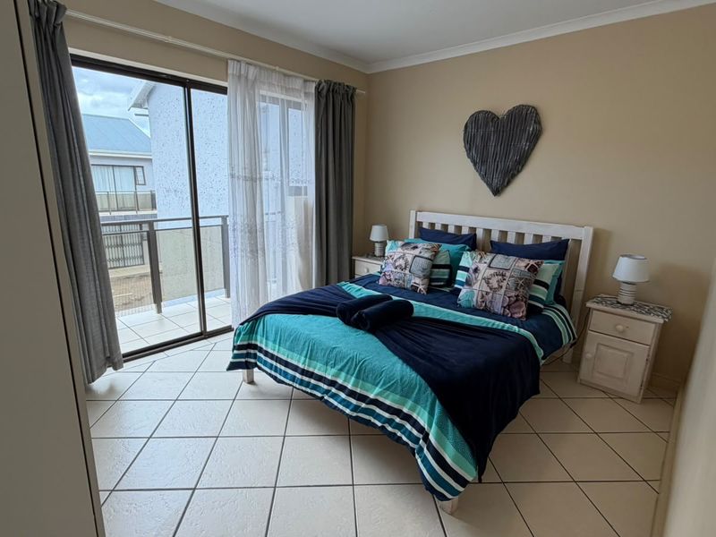 A bedroom featuring tiled flooring and a sliding glass door providing access to an outdoor balcony area.