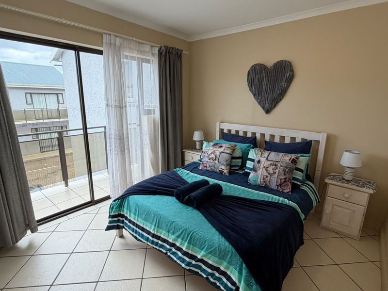 A bedroom featuring tiled flooring and a sliding glass door providing direct access to an outdoor balcony area.