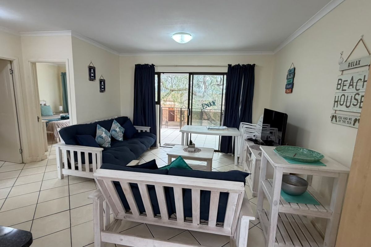 A bright living room featuring tiled flooring and a sliding glass door providing access to an outdoor balcony area.