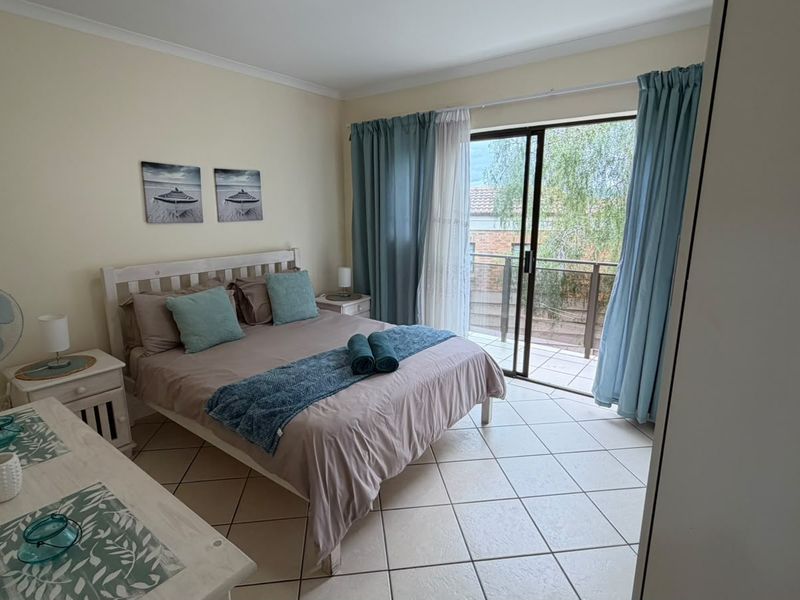 A bedroom featuring ceramic floor tiles, a built-in wardrobe, and a sliding glass door providing access to a private balcony.
