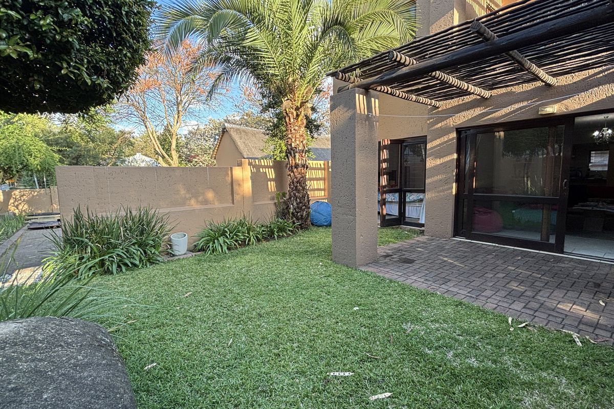 A private rear garden featuring a paved patio area with a pergola, accessible via sliding glass doors from the main living space.