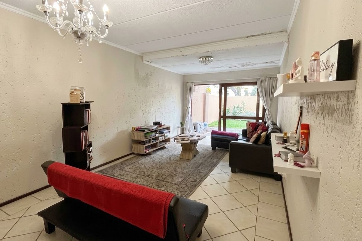 Living room featuring tiled flooring and sliding glass doors leading to the exterior, requiring ceiling and wall repairs due to visible water damage.
