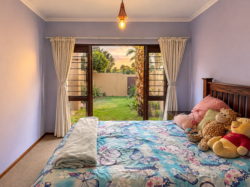 A bedroom featuring carpeted flooring and a sliding glass door that opens to a private garden area, providing natural light and outdoor access.