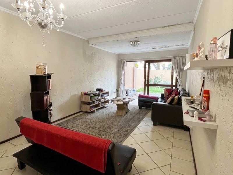 Living room featuring tiled flooring and sliding glass doors leading to the exterior, requiring ceiling and wall repairs due to visible water damage.
