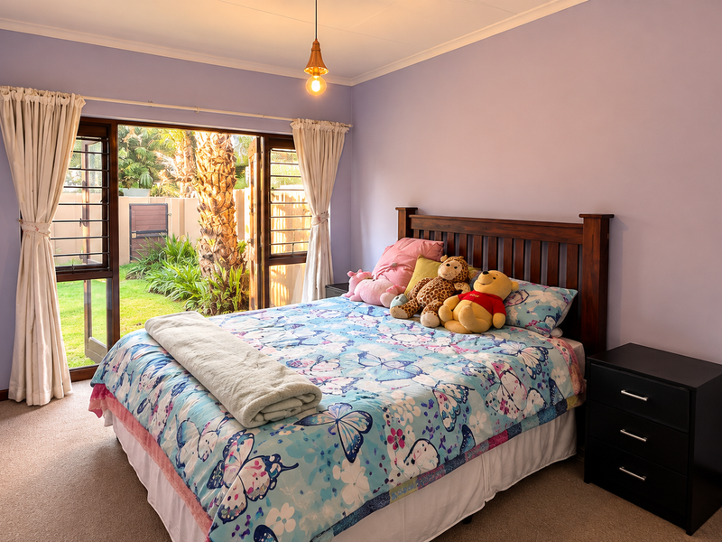 A bedroom featuring carpeted flooring and a sliding glass door that opens to a private garden area, providing natural light and outdoor access.