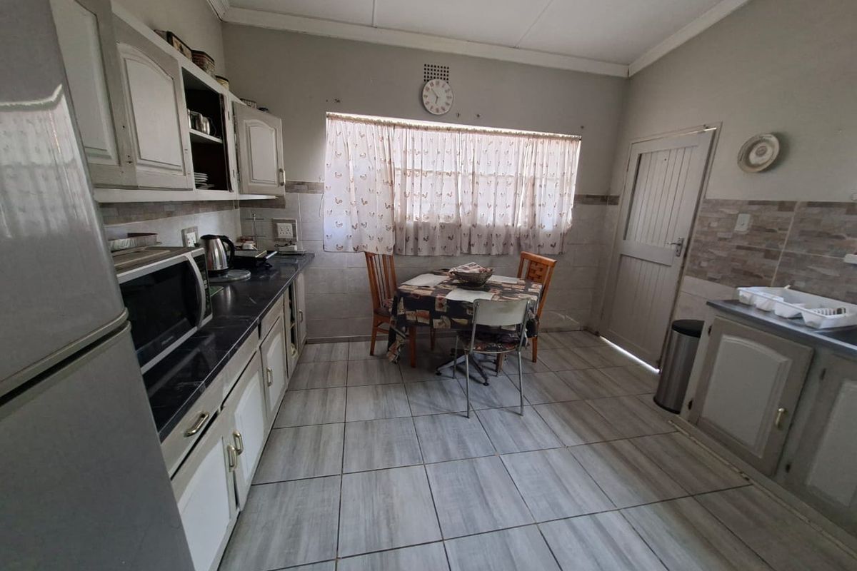 A functional kitchen featuring fitted cabinetry, laminate countertops, and tiled flooring, offering a practical layout with space for a small dining area.