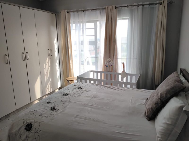 A well-lit bedroom featuring built-in cupboards and tiled flooring, offering a functional and comfortable living space.