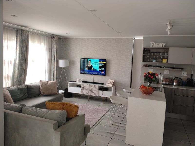 An open-plan living and kitchen area featuring a modern kitchen island, tiled flooring, and recessed lighting, creating a functional and cohesive living space.