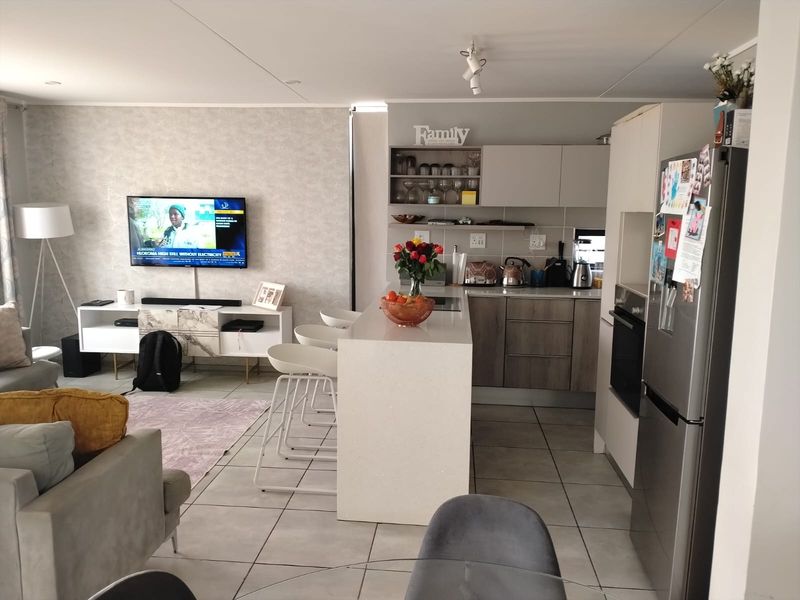 An open-plan living and kitchen area featuring a central island, modern cabinetry, and tiled flooring, creating a functional and connected living space.
