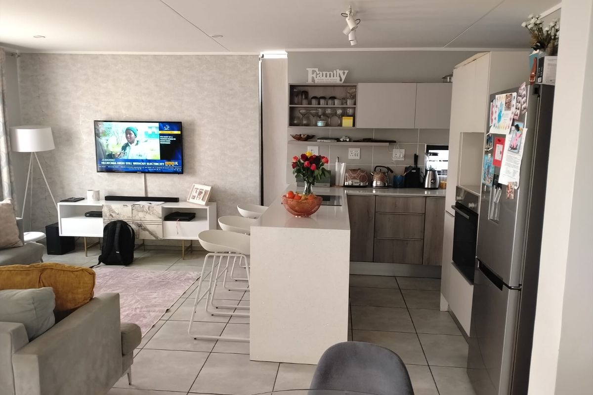 An open-plan living and kitchen area featuring a central island, modern cabinetry, and tiled flooring, creating a functional and connected living space.