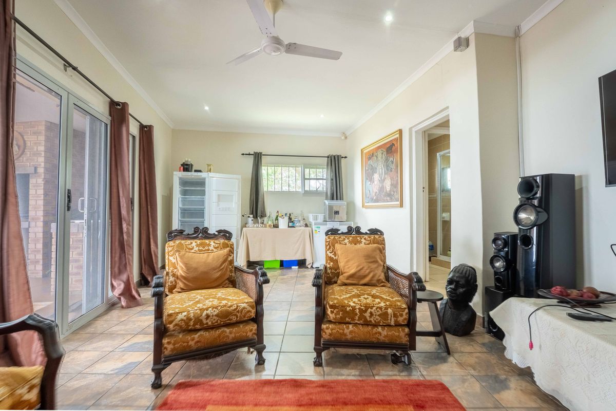 A spacious living area featuring tiled flooring, a ceiling fan, and large sliding glass doors providing access to the outdoor patio area.