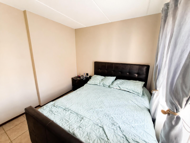 A standard bedroom featuring neutral wall finishes and tiled flooring, providing a functional and well-lit sleeping space.