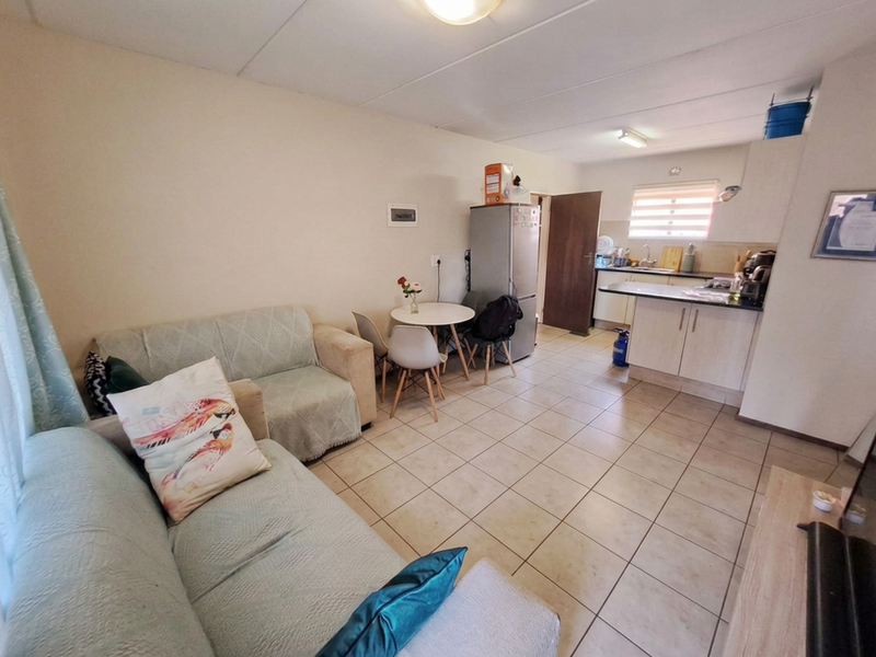 Open plan living area featuring tiled flooring and a functional kitchen with built-in cabinetry and countertop space.