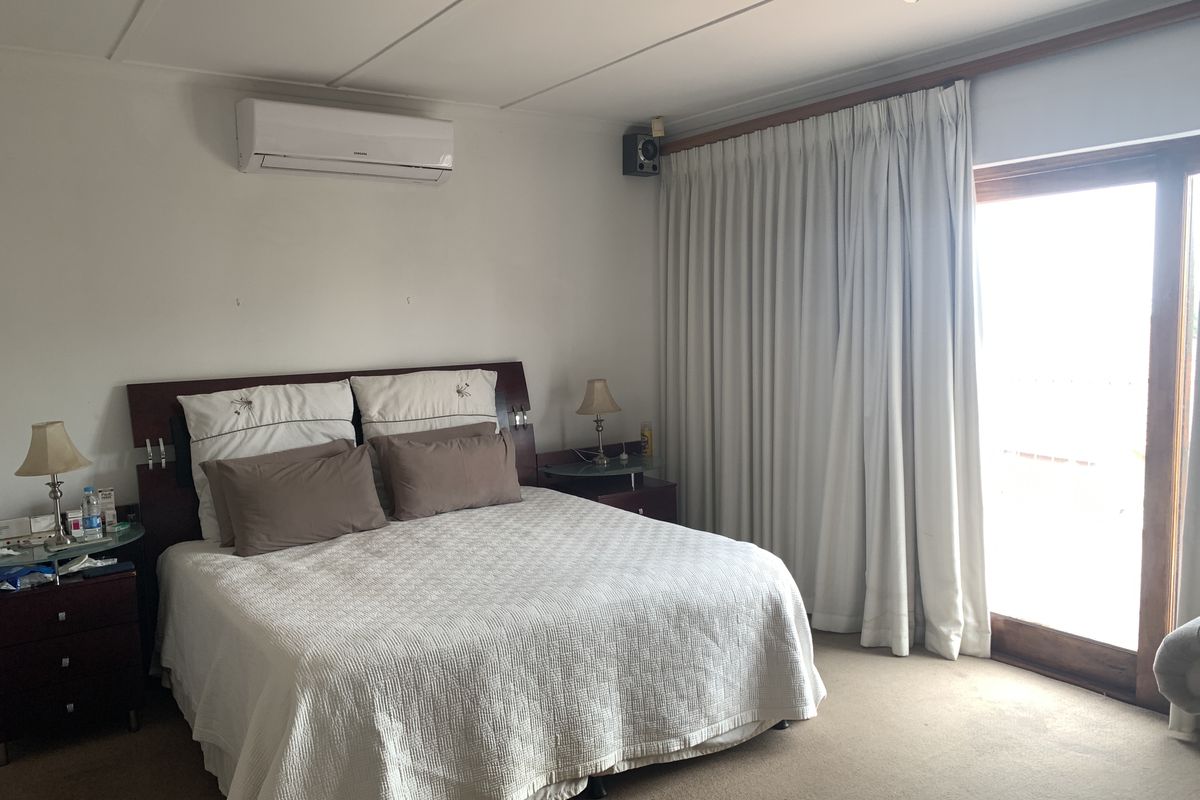 Spacious bedroom featuring carpet flooring, a split-system air conditioner, ceiling fan, and direct access to an outdoor area through a sliding glass door.