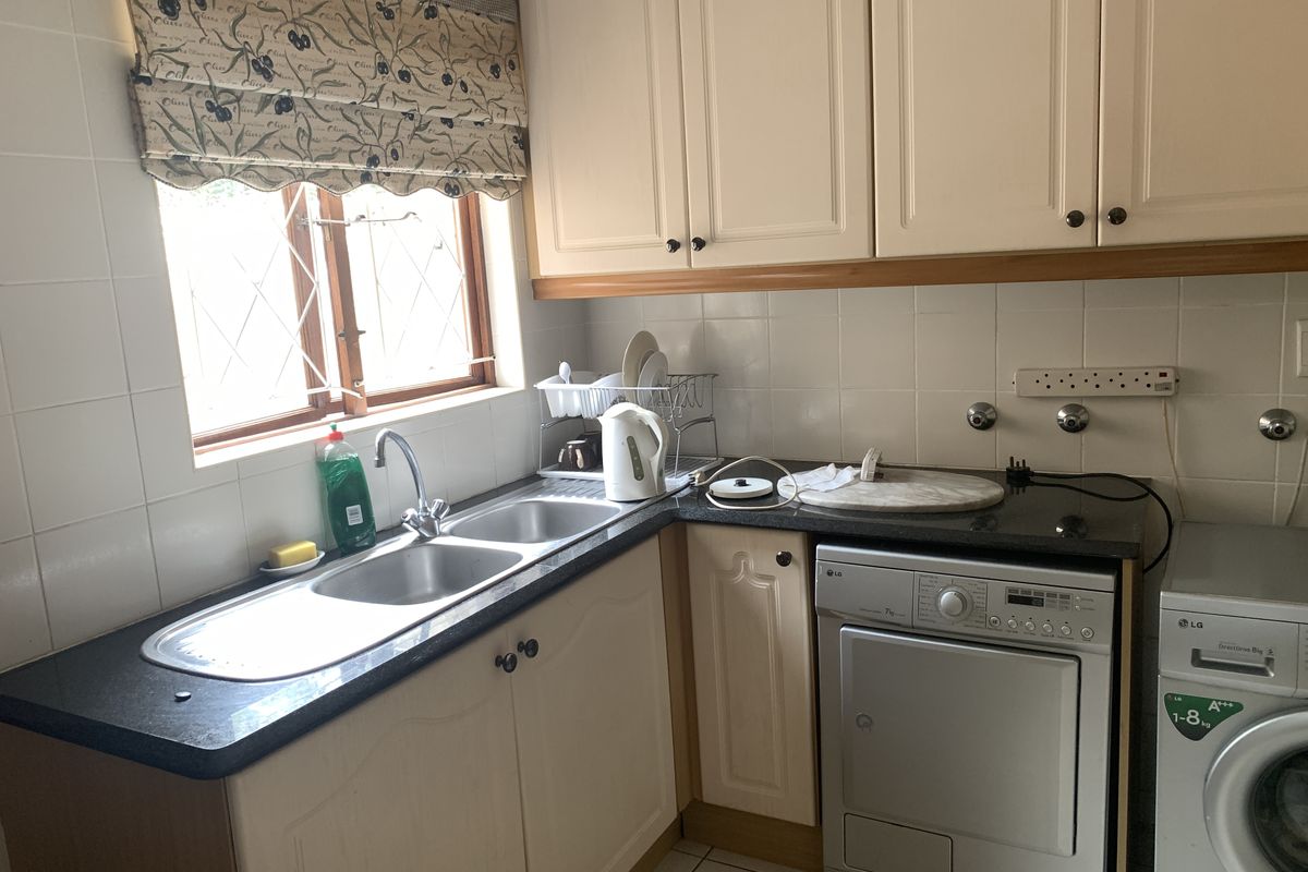 A functional kitchen area featuring double basin sink, granite countertops, and ample cabinetry, providing a practical space for daily household tasks.