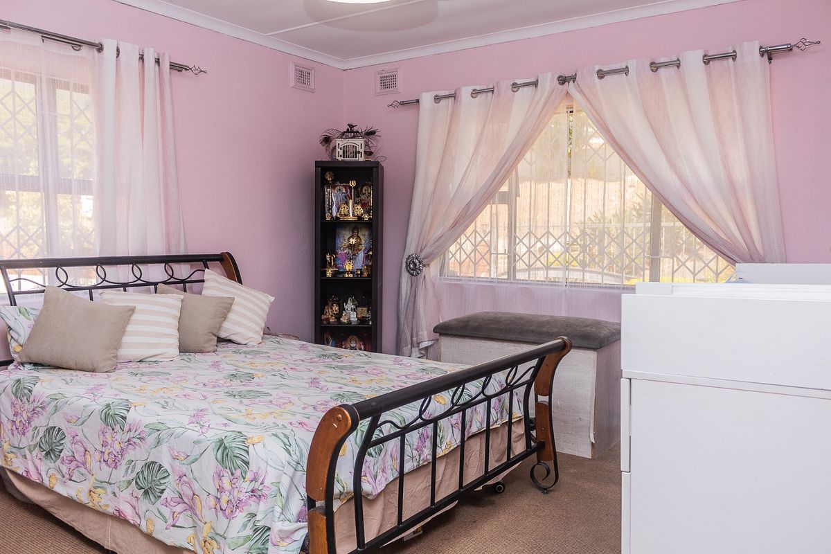 A bedroom featuring carpet flooring and windows fitted with security gates.