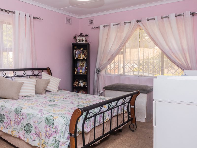 A bedroom featuring carpet flooring and windows fitted with security gates.