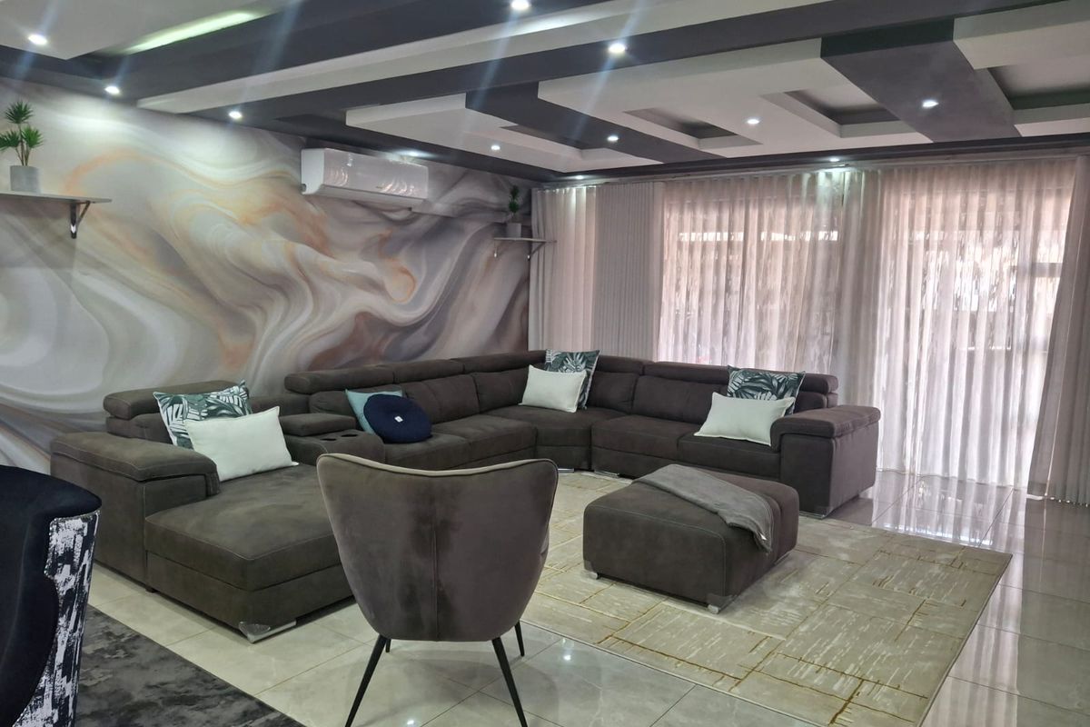 Spacious living room featuring a modern recessed ceiling with downlights, tiled flooring, and a decorative feature wall with an integrated air conditioning unit.