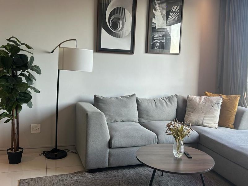A bright and modern living room featuring large windows with natural light and neutral tiled flooring.