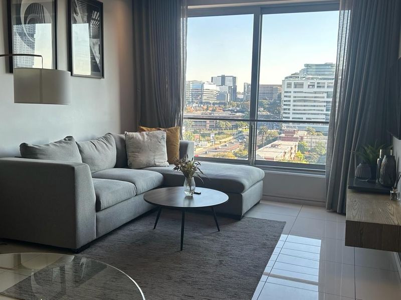A modern living room featuring large floor-to-ceiling windows with urban views, tiled flooring, and a sleek floating media console.