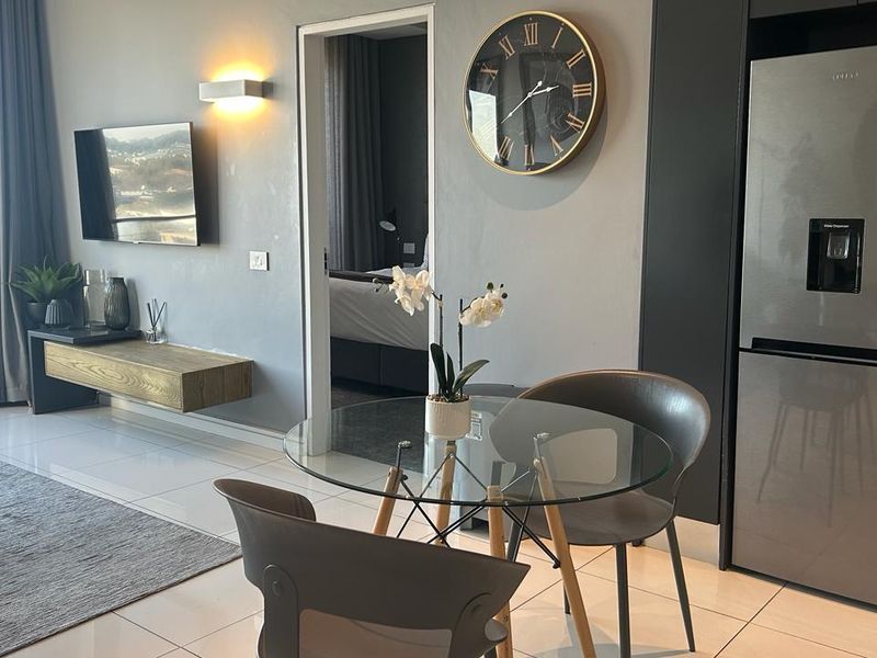 Modern open-plan living area featuring sleek tiled floors, a floating media console, and integrated kitchen cabinetry, offering a contemporary and functional layout.