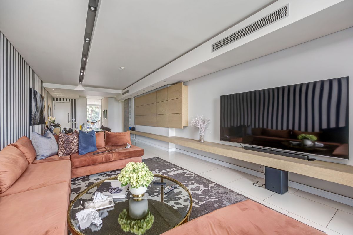 Modern living room featuring sleek built-in cabinetry, a floating timber shelf, ducted air conditioning, and high-quality tiled flooring.