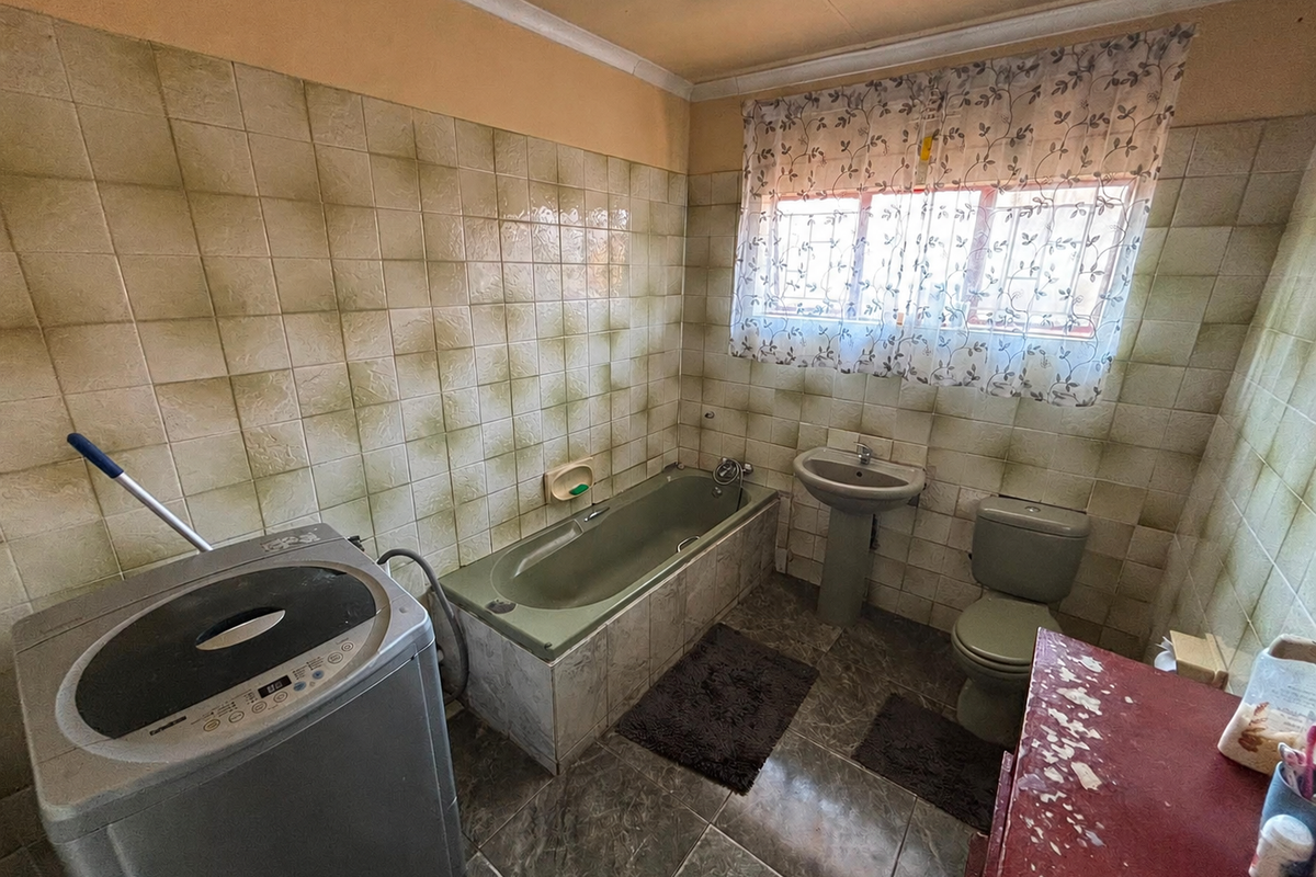 A dated bathroom featuring a built-in bathtub, pedestal basin, and toilet with original wall tiling, offering significant potential for modernization and renovation.