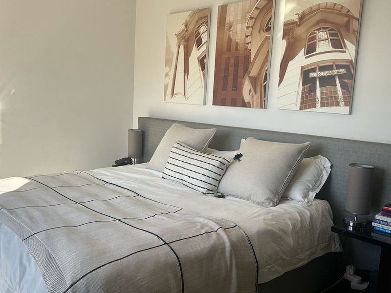 A well-maintained bedroom featuring a neutral color palette and a large built-in headboard, creating a comfortable and modern sleeping space.