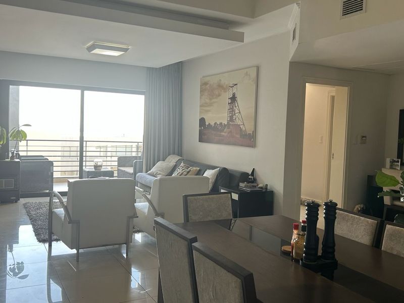 Spacious open-plan living and dining area featuring tiled floors, recessed ceiling details, and large sliding doors leading to a private balcony.