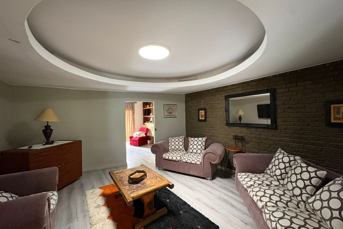 Living room featuring a distinctive circular recessed ceiling detail, exposed brick accent wall, and modern laminate flooring.