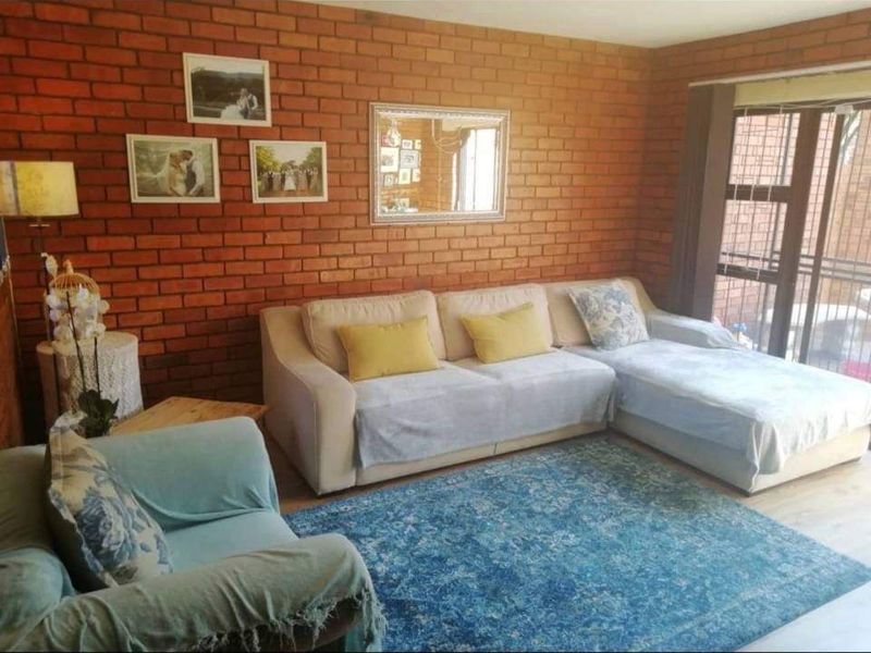 A cozy living room featuring a prominent exposed brick feature wall and large sliding glass doors that provide natural light and outdoor access.