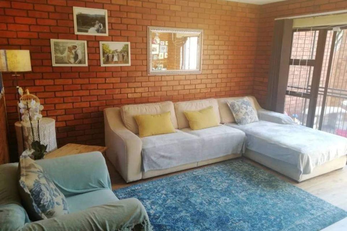 A cozy living room featuring a prominent exposed brick feature wall and large sliding glass doors that provide natural light and outdoor access.