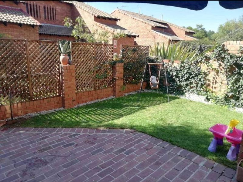 A private rear garden featuring brick paving, a well-maintained lawn, and brick boundary walls with decorative wooden lattice screening.
