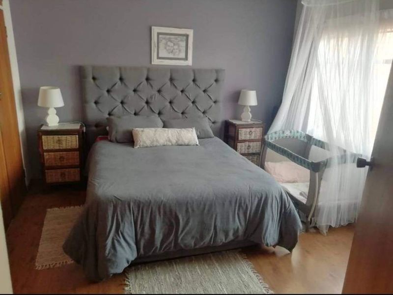A cozy bedroom featuring laminate flooring and a neutral wall finish, providing a comfortable and functional sleeping space.