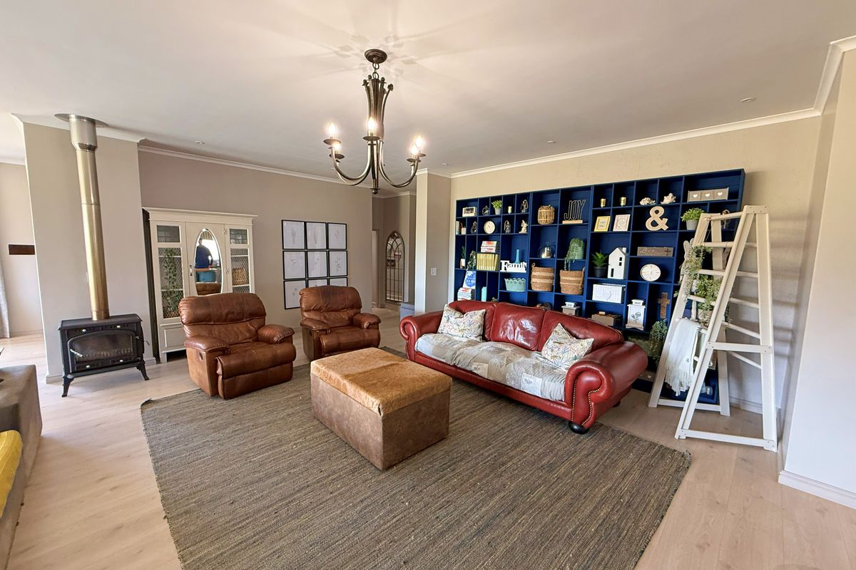 Spacious living room featuring light laminate flooring, a prominent wood-burning fireplace, and a large built-in blue shelving unit.