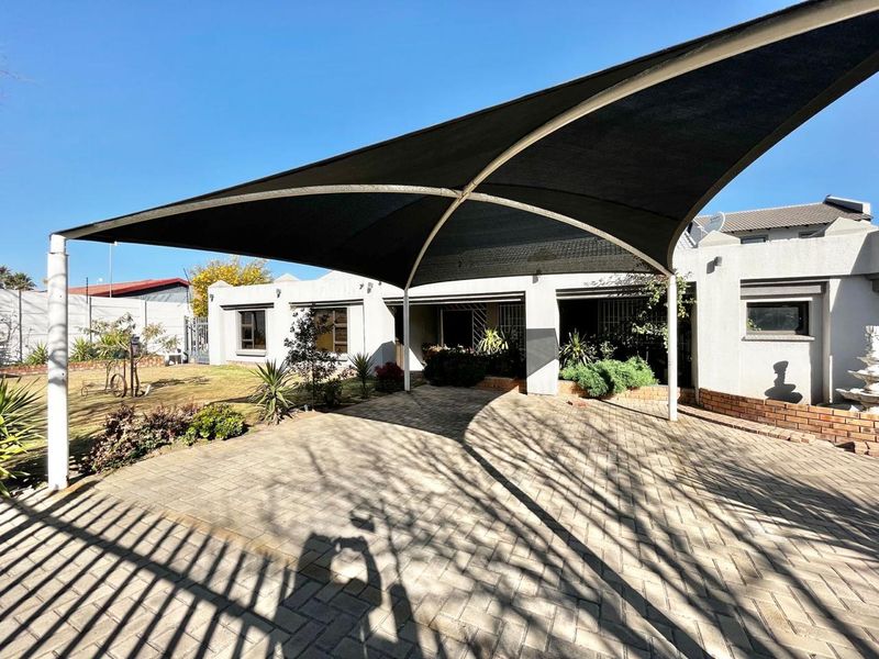 Rear exterior view of the townhouse featuring a paved patio area covered by a large shade sail and a small garden space.