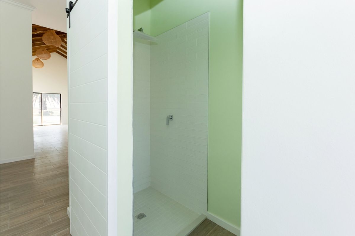 A clean, modern shower enclosure featuring white subway-style wall tiles and a minimalist shower mixer, set within a bright, neutral-toned bathroom space.