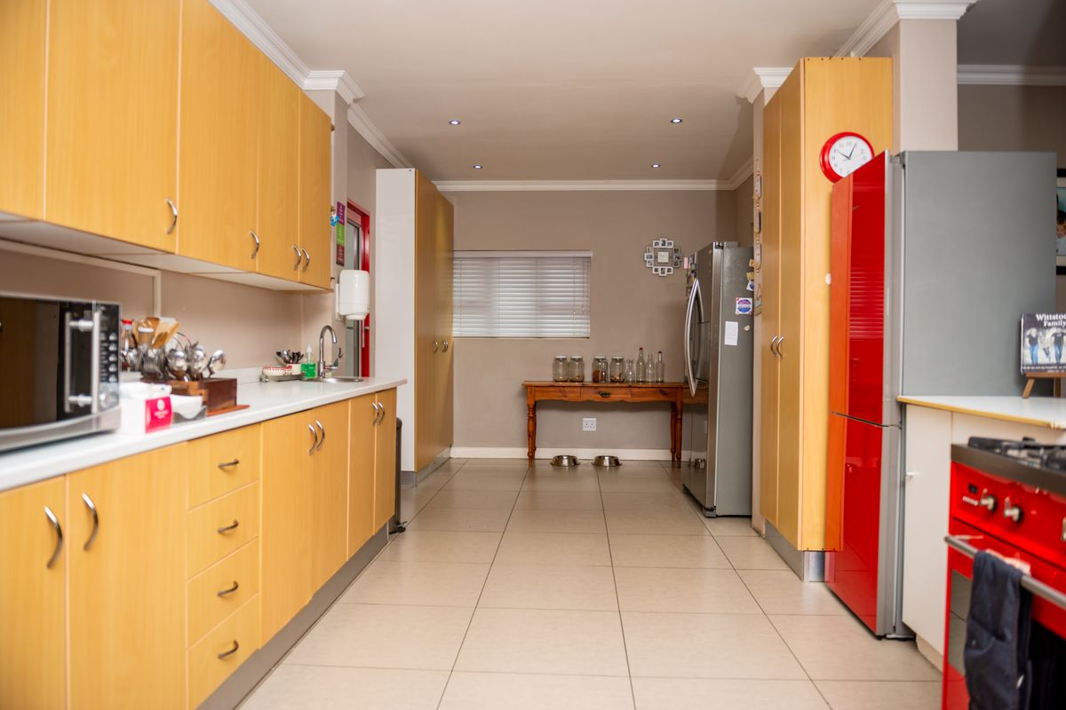 A functional kitchen featuring light wood cabinetry, tiled flooring, recessed lighting, and a practical layout with ample storage and counter space.