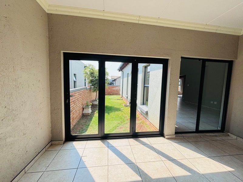 Covered patio area featuring tiled flooring and modern black aluminium stacker doors opening onto a private garden space.