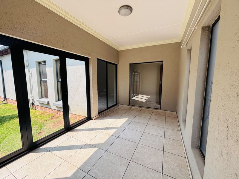 A covered patio area featuring tiled flooring and large sliding glass doors providing access to the interior and garden views.