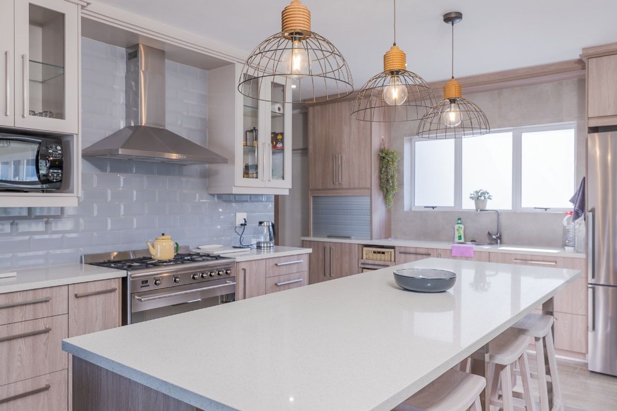 Modern kitchen featuring a large central island with quartz countertops, subway tile backsplash, stainless steel appliances, and ample custom cabinetry.