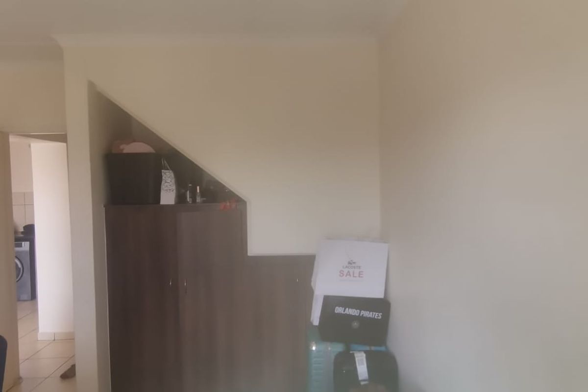 A living area featuring a built-in cupboard under the staircase, with a view into an adjacent room.