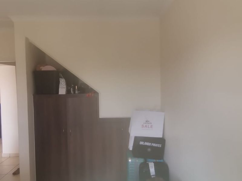 A living area featuring a built-in cupboard under the staircase, with a view into an adjacent room.