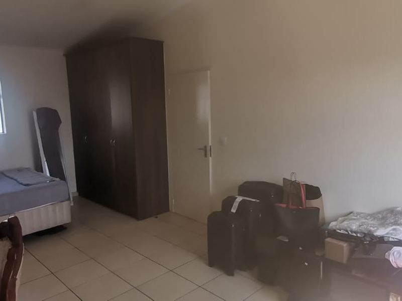 A bedroom featuring tiled flooring and a built-in wardrobe, offering a functional space with natural light from a single window.