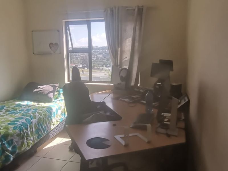 A functional bedroom featuring tiled flooring and a window with natural light, suitable for use as a sleeping area or home office.
