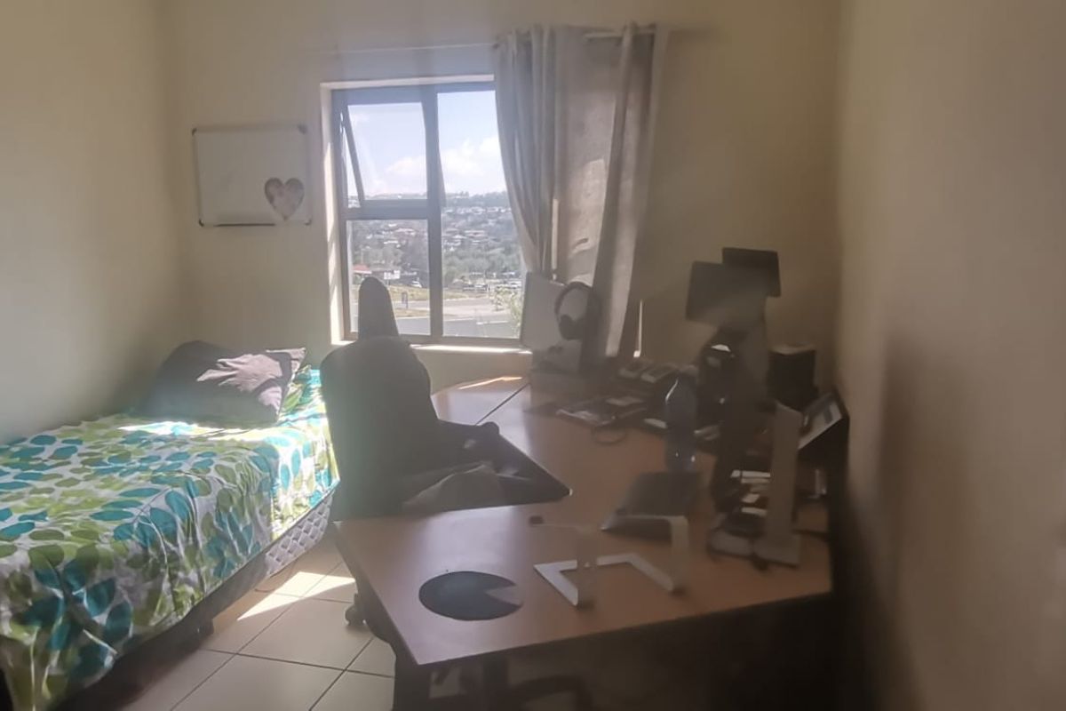A functional bedroom featuring tiled flooring and a window with natural light, suitable for use as a sleeping area or home office.