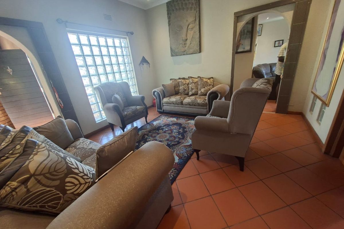 A living room featuring terracotta floor tiles, a glass block window, and arched doorways leading to adjacent spaces.