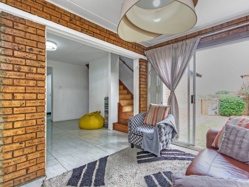 Living room featuring exposed brick walls, tiled flooring, and a sliding glass door providing access to the outdoor area.