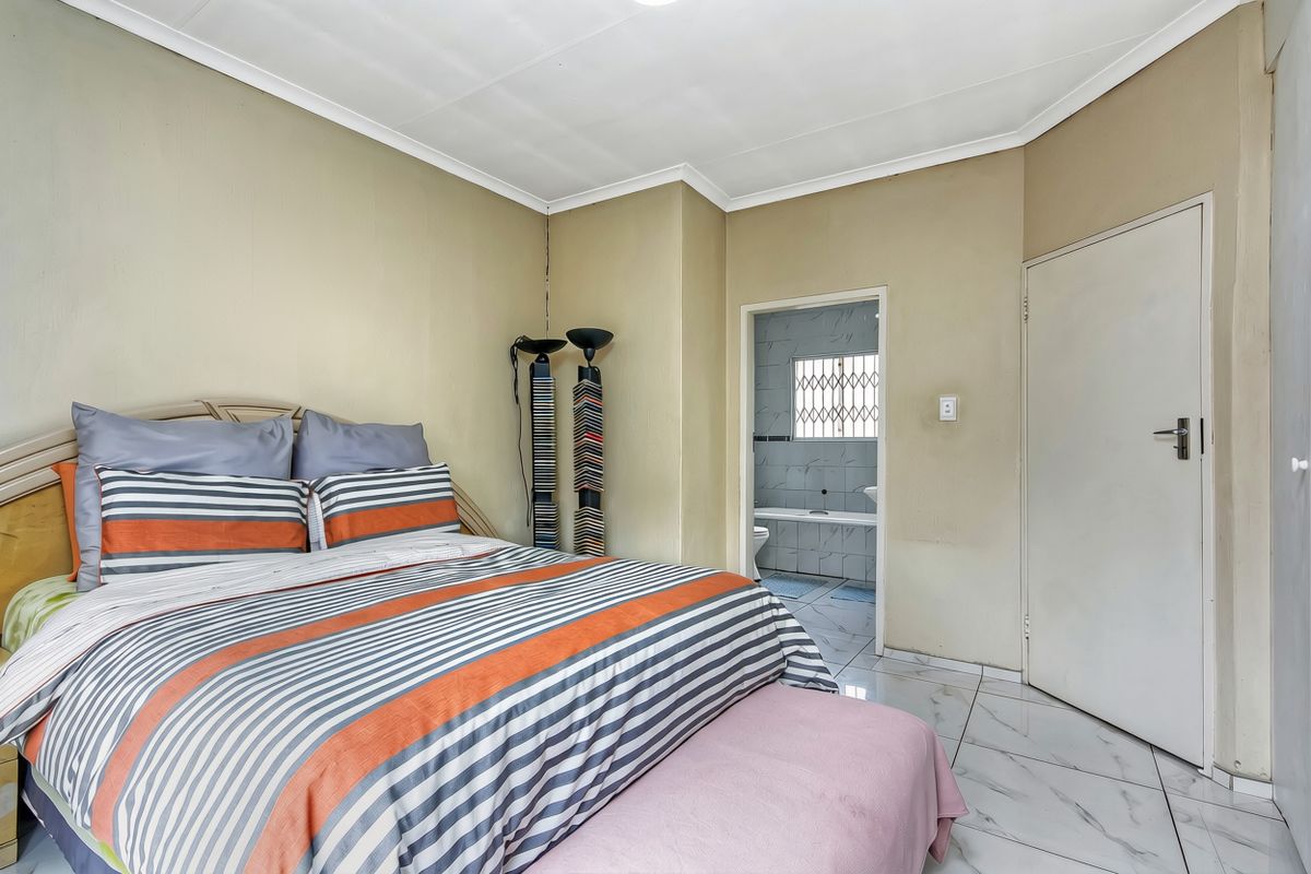 A bedroom featuring tiled flooring and direct access to an en-suite bathroom, offering a functional layout with neutral wall tones.