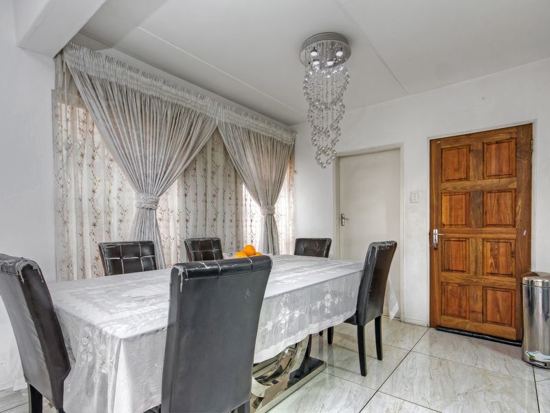 A dining room featuring tiled flooring, a decorative crystal chandelier, and a solid wooden panel door.